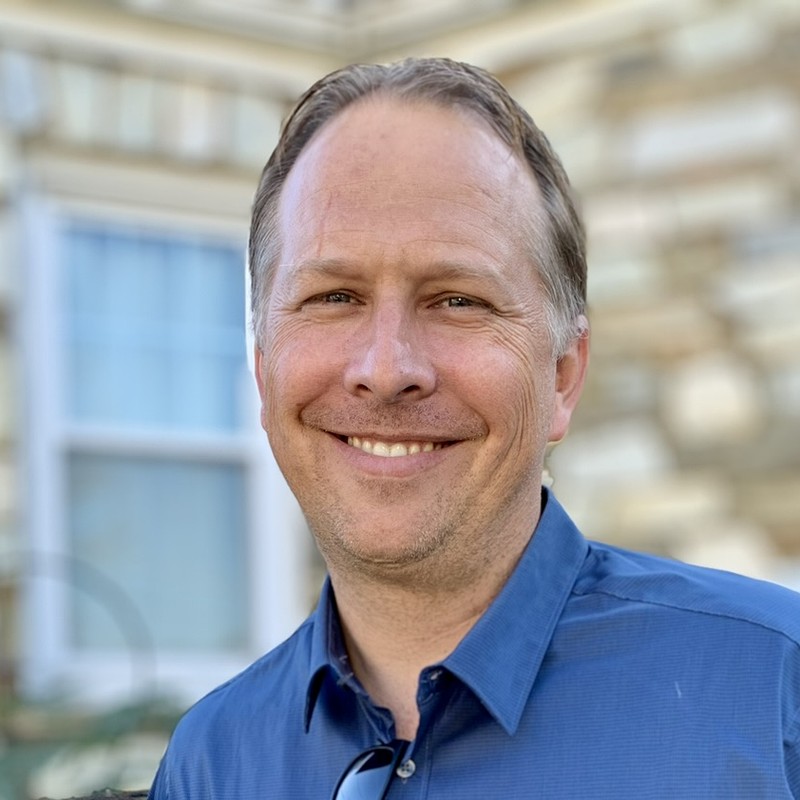 Reverend Ryan Irmer, smiling, in a blue collared shirt.
