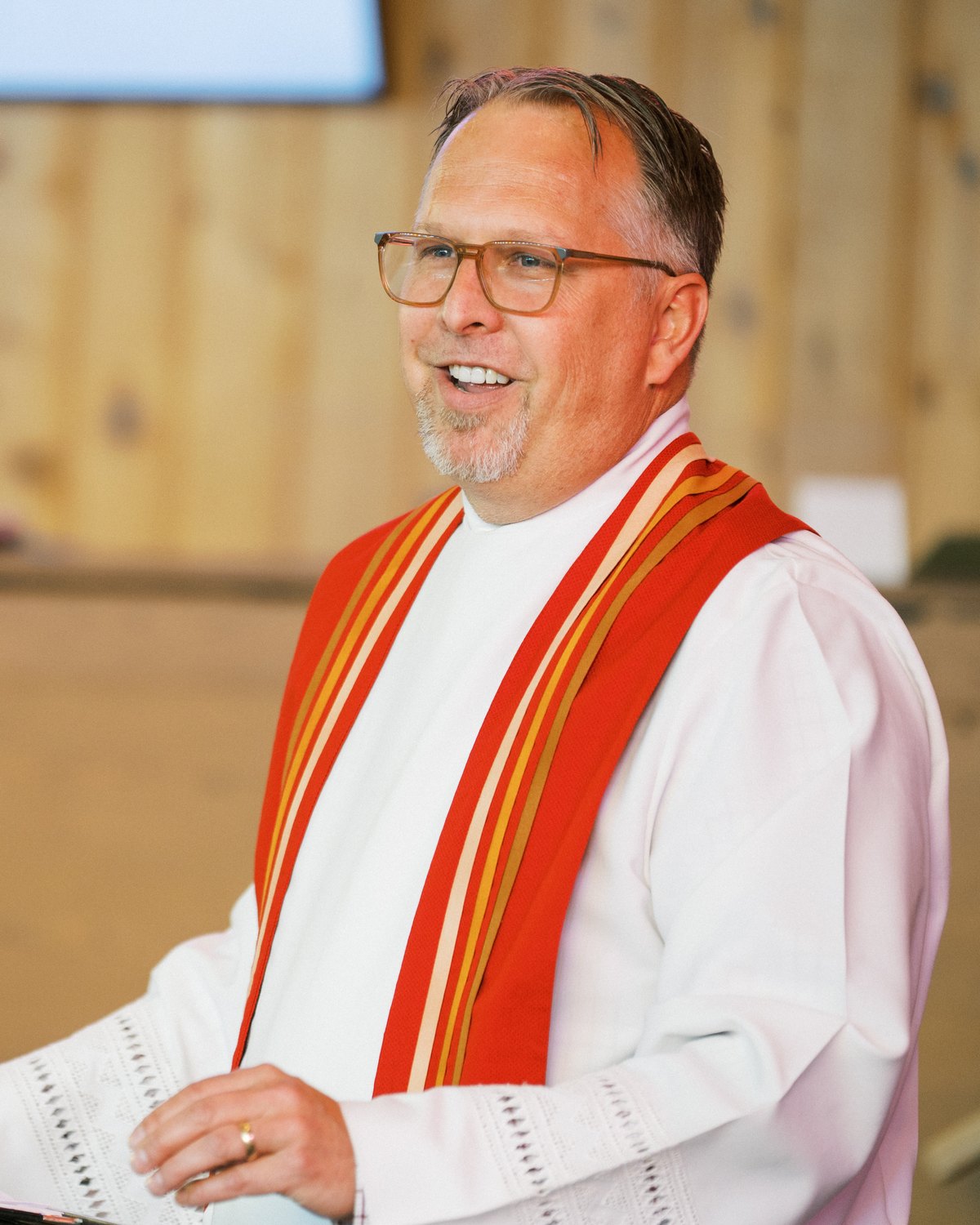 Rev. Ryan Irmer, in an alb and red stole, speaking at Wilson Memorial Union Church.